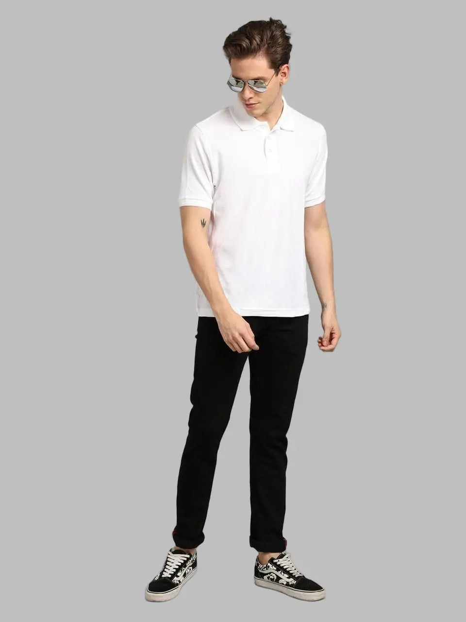 Man wearing a white polo shirt, black pants, and black sneakers on a gray background