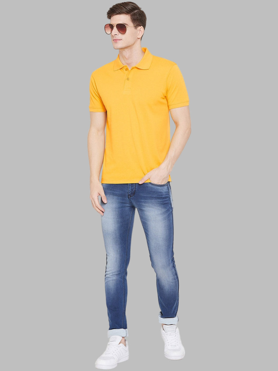 Man wearing a yellow polo shirt and blue jeans on a white background