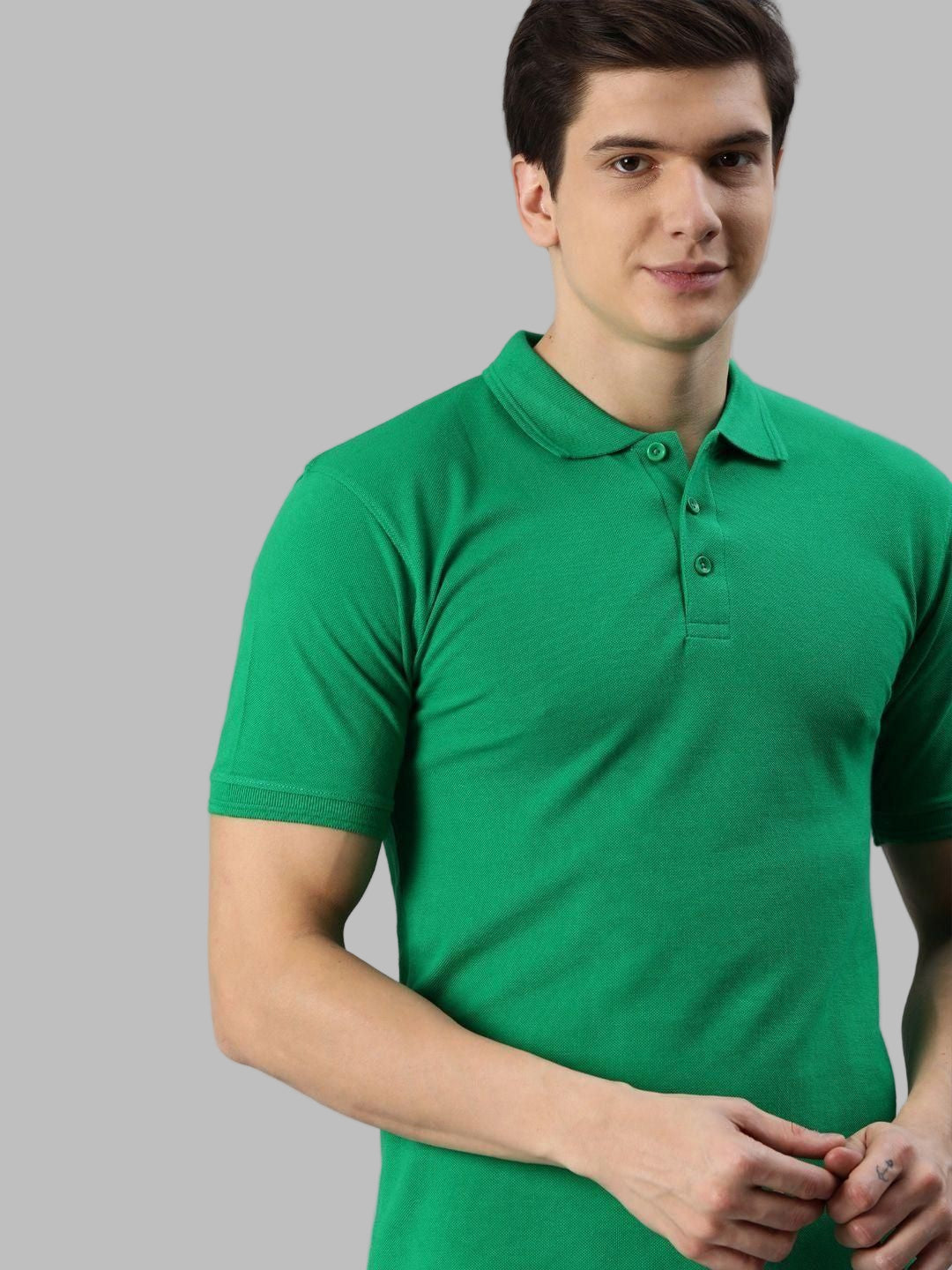 Man wearing a green polo shirt against a gray background