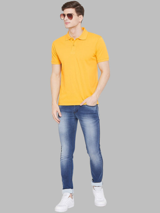 Man wearing a yellow polo shirt and blue jeans on a white background