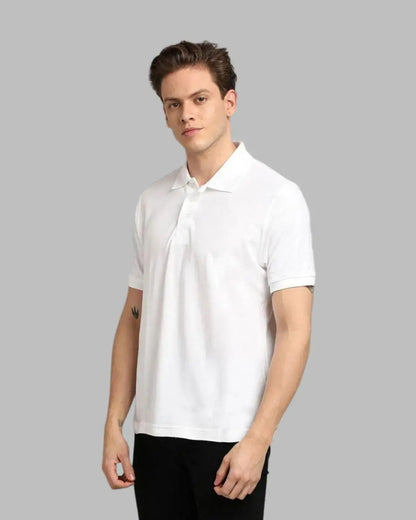 Man wearing a white polo shirt against a gray background